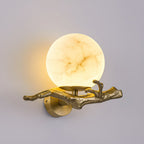 The Clérachic Alabaster Globe Wall Sconce lit at an angle, veining running across the stone while the brass arm catches the light.