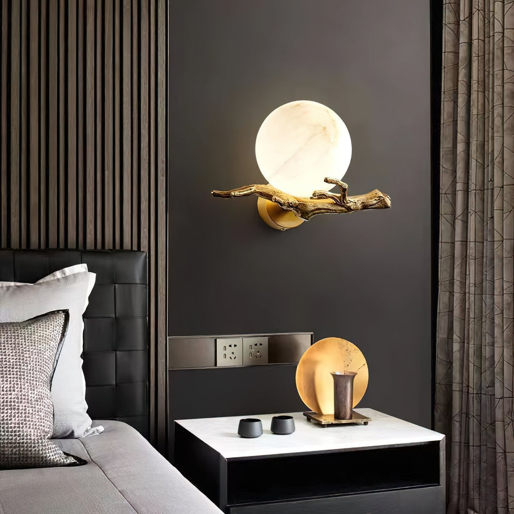 Clérachic Alabaster Globe Wall Sconce on a dark bedroom wall above a nightstand, casting a soft pool beside a leather headboard.