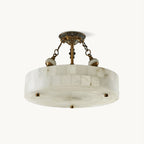 This Clérachic ceiling light has a drum of pale alabaster blocks hung from antique brass chains and a patterned canopy, on a white backdrop.