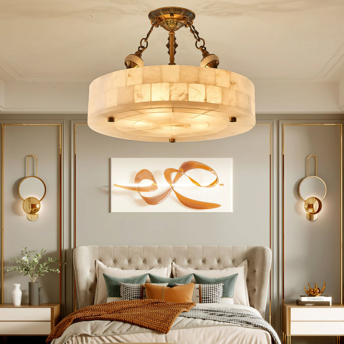 A Clérachic alabaster ceiling light glows above a bed with a tufted headboard, flanked by gold wall lights and a rust throw.