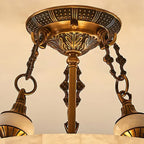 Close view of the patterned brass canopy, chain links and alabaster finials that hold up this Clérachic ceiling light.