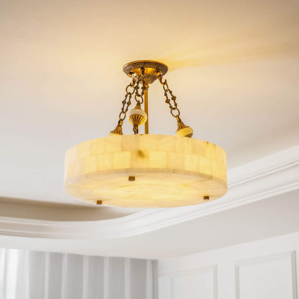 Lit Clérachic alabaster ceiling light with golden veining showing through the stone, under a white ceiling with stepped moulding.