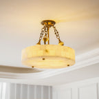 Lit Clérachic alabaster ceiling light with golden veining showing through the stone, under a white ceiling with stepped moulding.