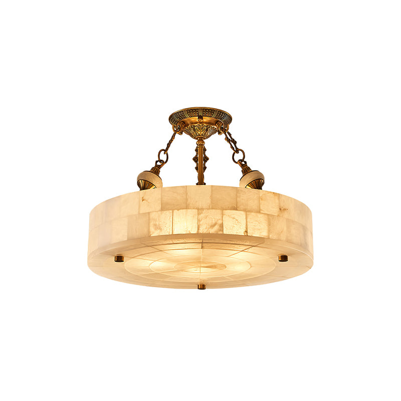 Smaller Clérachic alabaster drum ceiling light with antique brass chains, cut out on a white backdrop and lit from within.