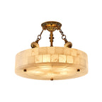 The largest alabaster drum of this Clérachic ceiling light, lit warm on a white backdrop, with brass chains and a patterned canopy.