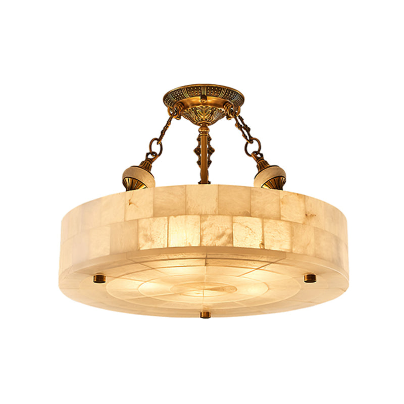 The largest alabaster drum of this Clérachic ceiling light, lit warm on a white backdrop, with brass chains and a patterned canopy.