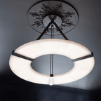 The Clérachic halo pendant seen from below, its lit ring against a charcoal ceiling.
