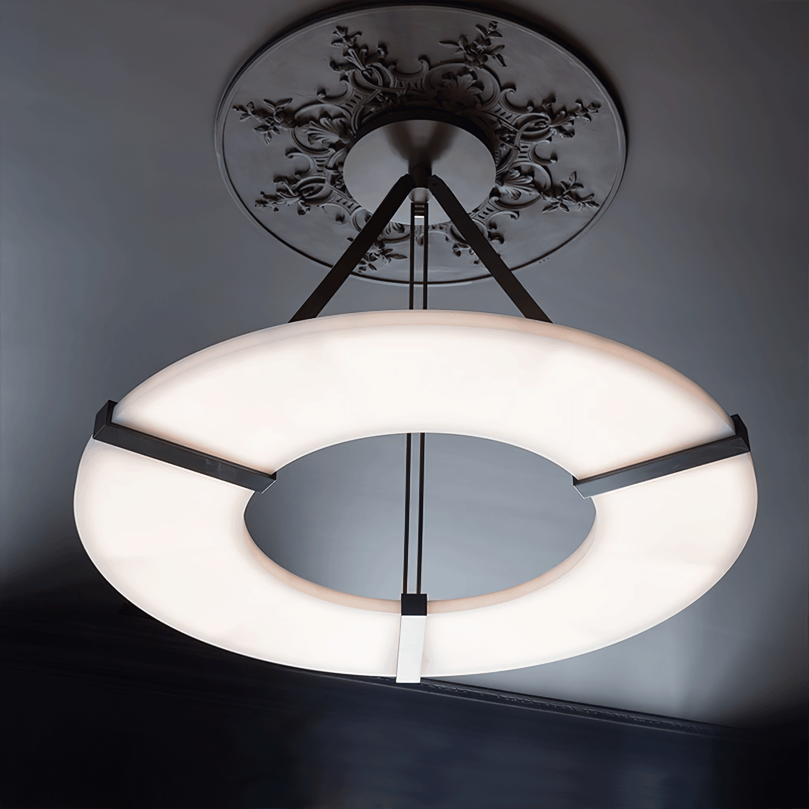 The Clérachic halo pendant seen from below, its lit ring against a charcoal ceiling.
