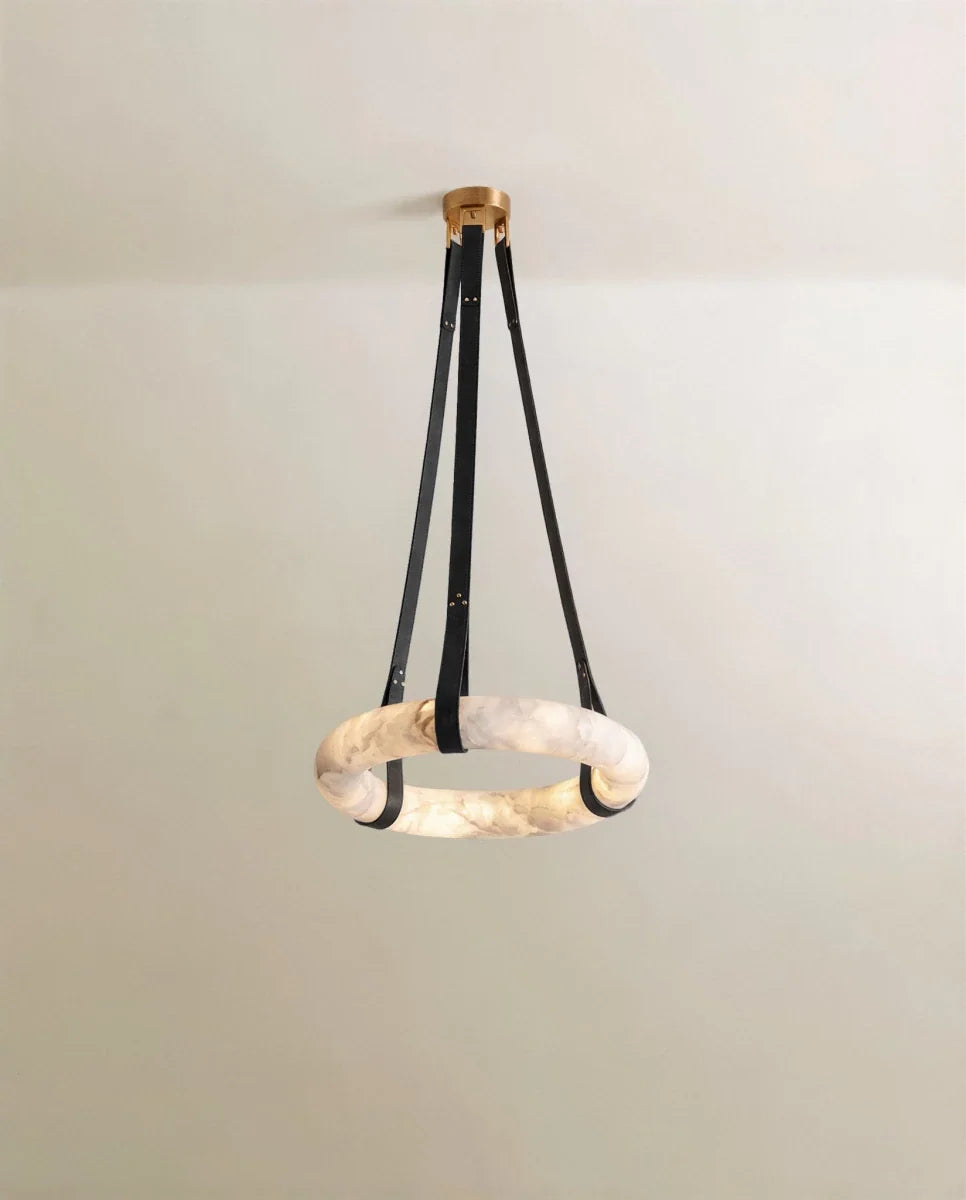 Clérachic alabaster ring pendant on three black leather straps with a gold canopy, the stone glowing against a pale wall.