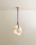 Clérachic alabaster ring pendant on a single tan leather strap from a round gold canopy, the stone softly lit.