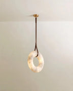 Clérachic alabaster ring pendant hanging from one dark brown leather strap and a round gold canopy, lit from within.