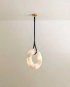Clérachic alabaster ring pendant hung from a single black leather strap and gold canopy, the veined stone glowing softly.