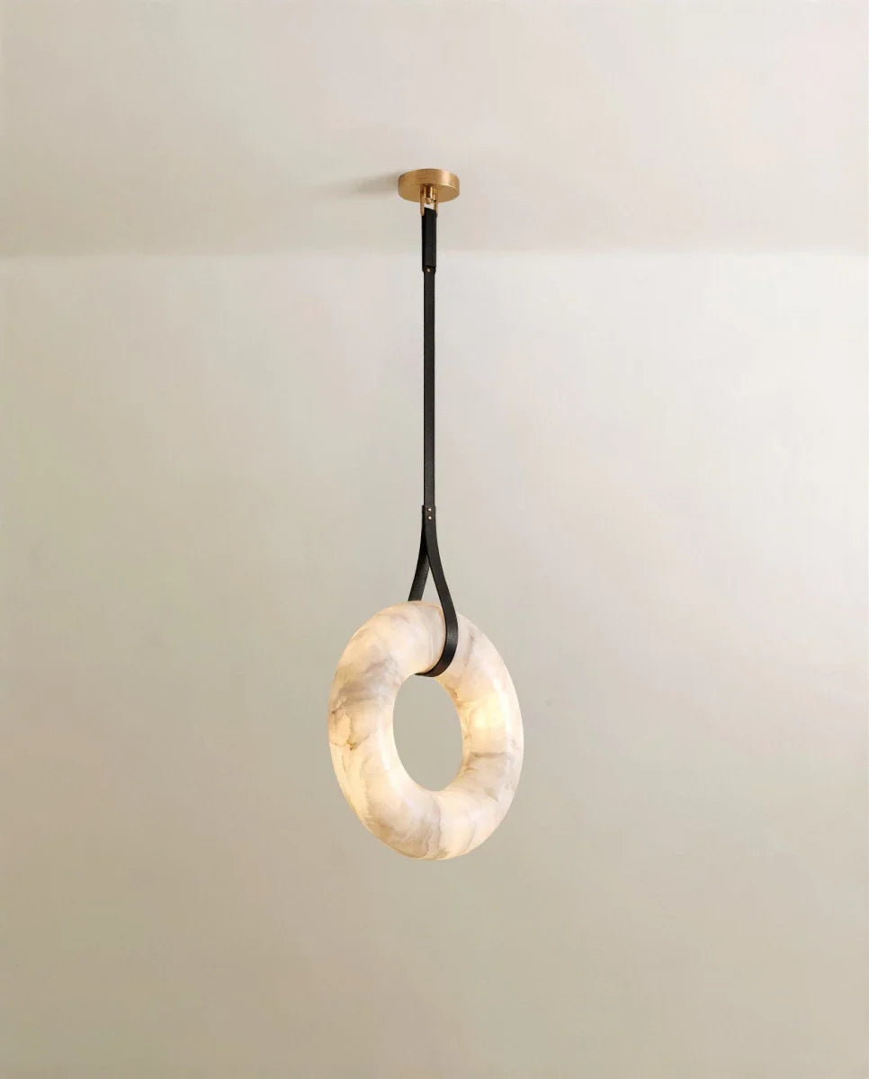 Clérachic alabaster ring pendant hung from a single black leather strap and gold canopy, the veined stone glowing softly.