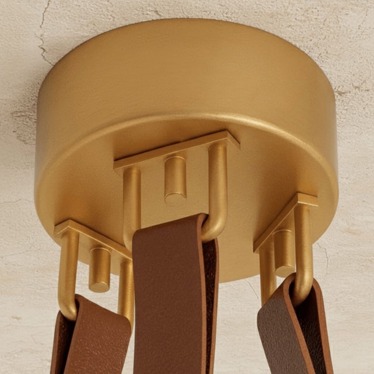 Clérachic gold ceiling canopy seen from below, with three tan leather straps hooked to gold loops on a textured plaster ceiling.