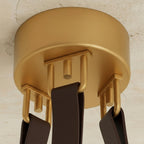 Clérachic gold ceiling canopy from below, three dark brown leather straps hooked to gold loops on a textured plaster ceiling.