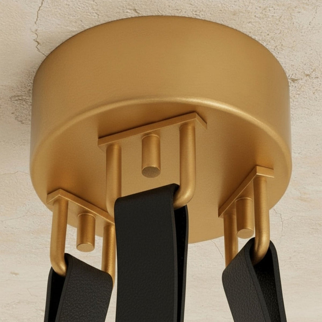 Clérachic gold ceiling canopy from below, with three black leather straps hooked to gold loops on a textured plaster ceiling.
