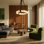 Clérachic alabaster ring pendant on dark leather straps hung over a glass coffee table in a living room with walnut joinery.