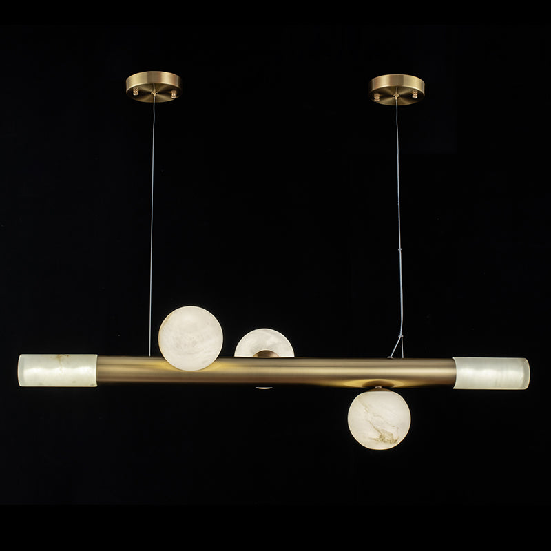Clérachic Alabaster Linear Bar Pendant Light in its three-globe form, brass bar and lit stone end caps against a black studio backdrop.