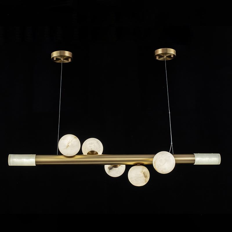 Five alabaster globes along the Clérachic Alabaster Linear Bar Pendant Light, with a lit stone cylinder closing each end of the bar.