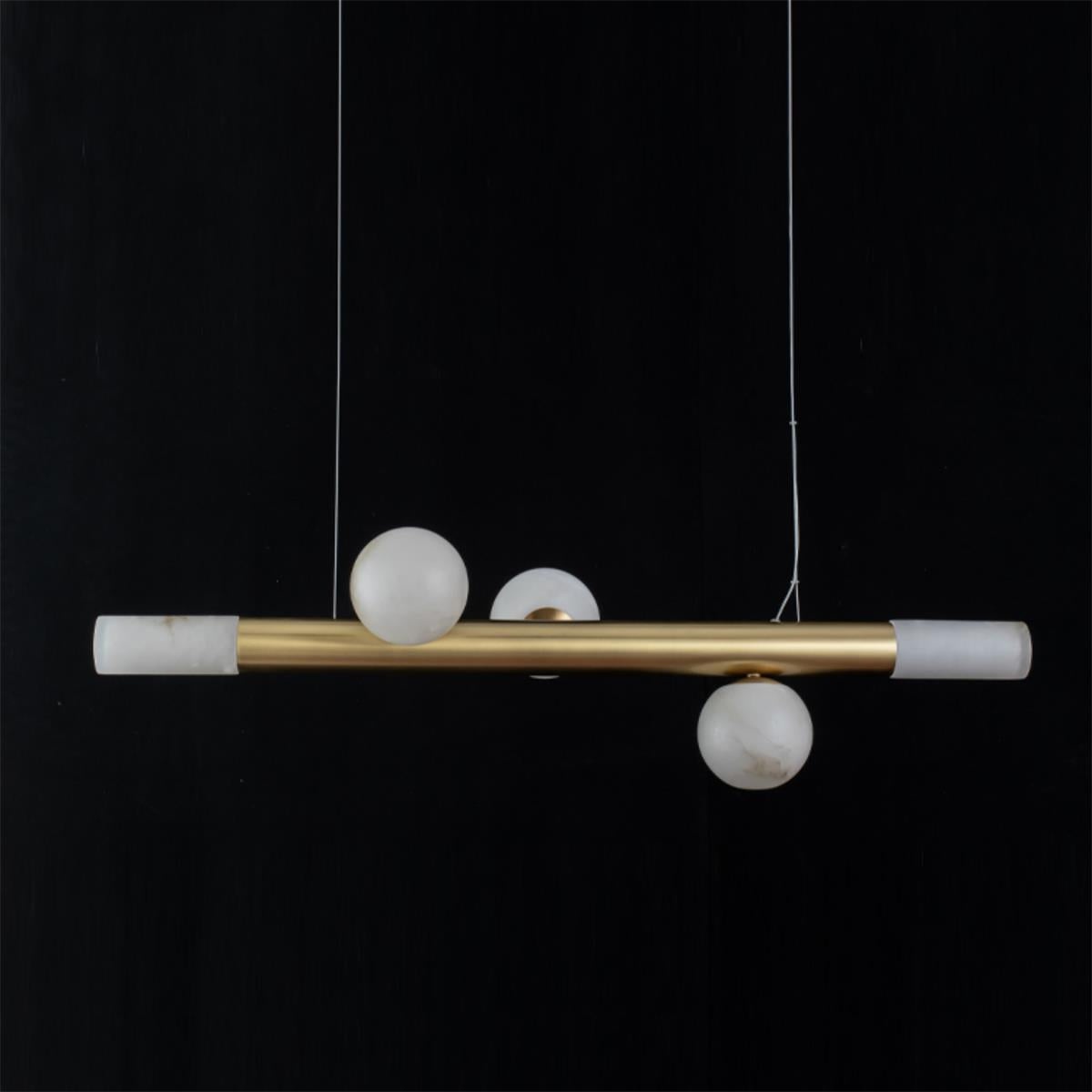 Clérachic Alabaster Linear Bar Pendant Light photographed level on black, three stone globes clustered at the centre of the brass bar.