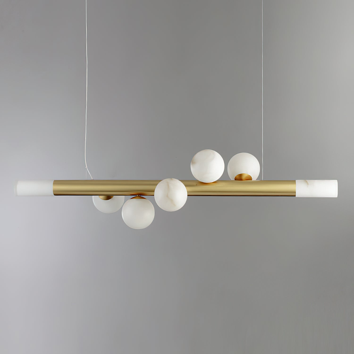 Five-globe Clérachic Alabaster Linear Bar Pendant Light on grey, the globes gathered mid-bar between lit stone end caps.