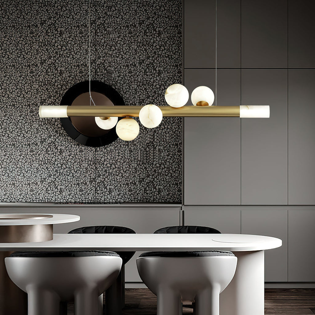 Clérachic Alabaster Linear Bar Pendant Light over a white oval kitchen table, hung against a terrazzo and grey cabinet wall.