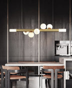 Clérachic Alabaster Linear Bar Pendant Light over a marble table in a dark oak kitchen with tan leather chairs.