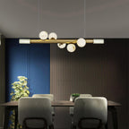 Clérachic Alabaster Linear Bar Pendant Light over a walnut dining table, framed by a blue wall and dark slatted panelling.