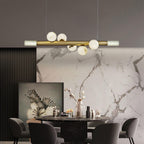 Clérachic Alabaster Linear Bar Pendant Light lighting a round black table dressed with cotton stems and a leaning bird print.