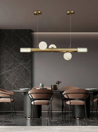 Three-globe Clérachic Alabaster Linear Bar Pendant Light above a fluted dining counter in a dark marble-clad room.