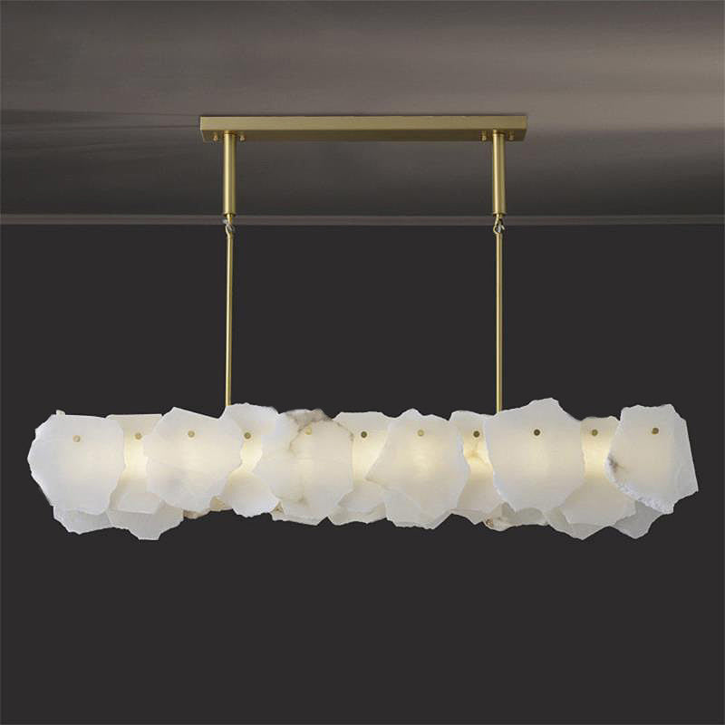 Clérachic alabaster linear chandelier lit against a dark ceiling, overlapping raw-edged stone slabs along a brass bar