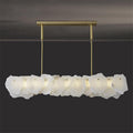 The Clérachic alabaster linear chandelier glowing in a dim room, its LED pushing an even band of light through the stone