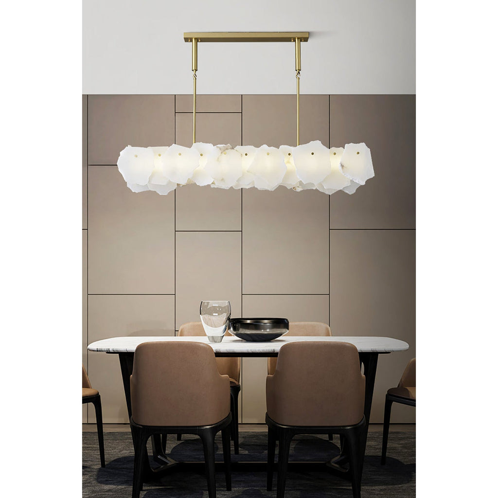 Clérachic alabaster linear chandelier lit above a marble dining table with tan leather chairs and a panelled taupe wall