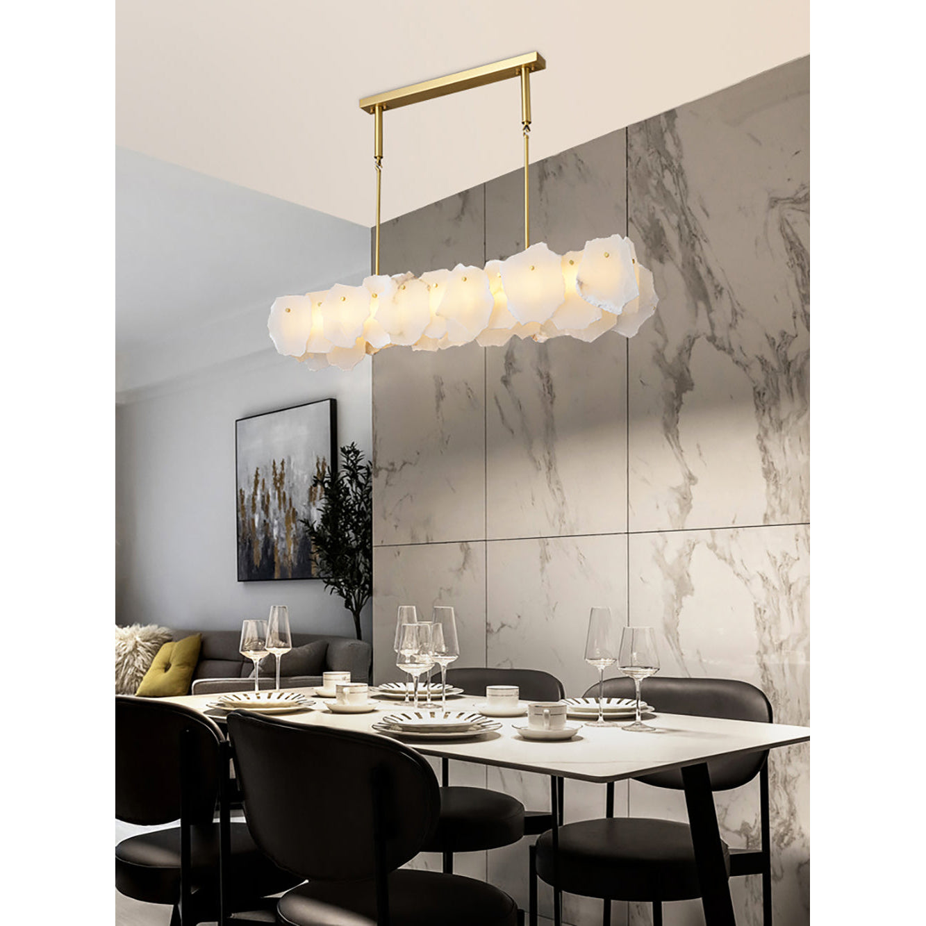 Clérachic alabaster linear chandelier above a laid dining table, wine glasses and plates set against a marble tile wall