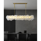 Clérachic alabaster linear chandelier lighting a dark dining room with a black slatted wall and charcoal dining chairs