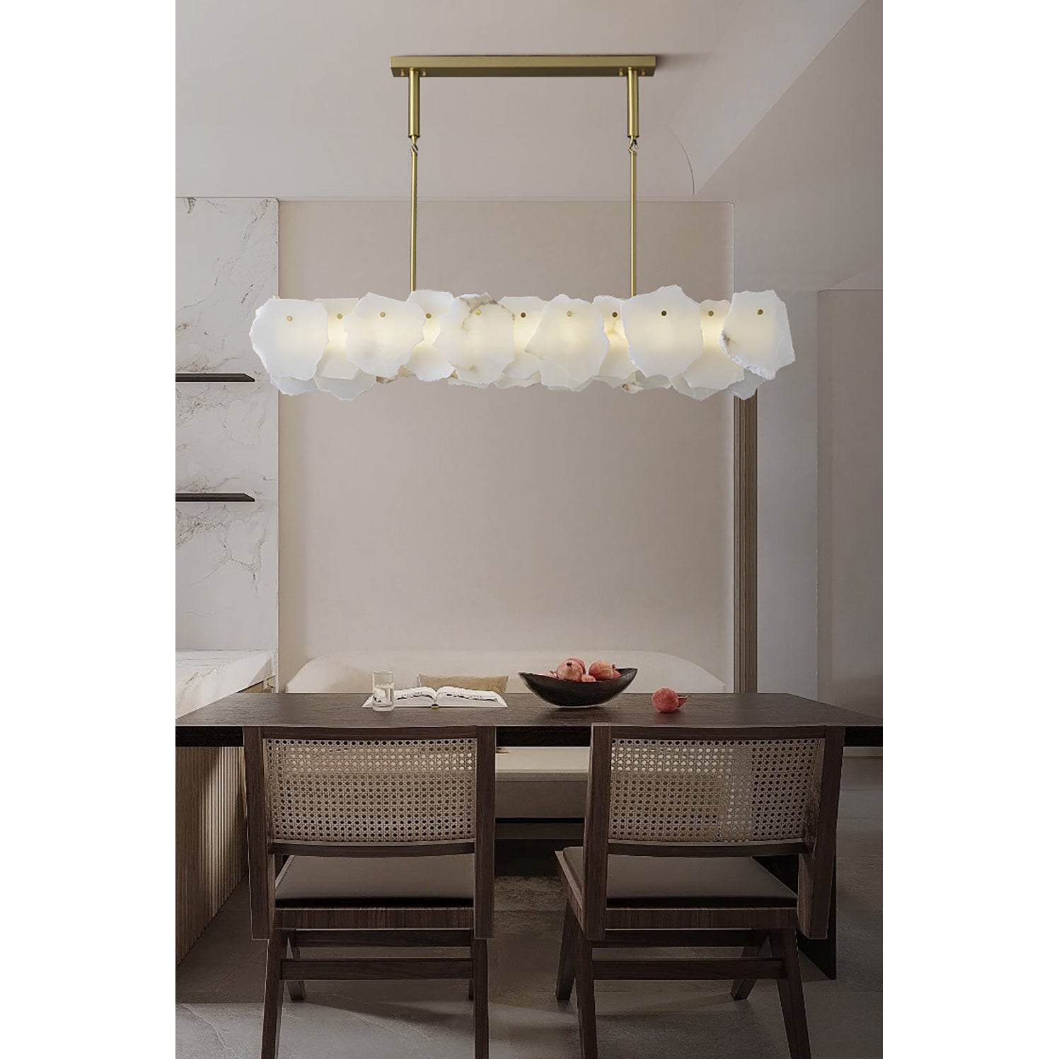 Clérachic alabaster linear chandelier above a dining table with cane-back chairs and a dark bowl of pomegranates