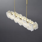 Three-quarter view of the Clérachic alabaster linear chandelier showing the brass bar and the LED behind the lapped slabs