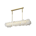 Clérachic alabaster linear chandelier unlit from a low angle, the raw stone edges reading as one pale block