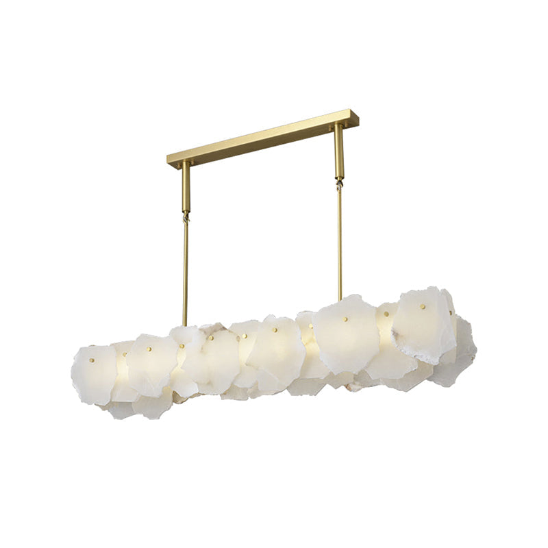 Clérachic alabaster linear chandelier unlit from a low angle, the raw stone edges reading as one pale block