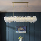 Clérachic alabaster linear chandelier lit against a navy panelled wall with framed art and white hydrangeas below