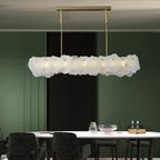 Clérachic alabaster linear chandelier over a white dining table in a deep green room with a black slatted panel