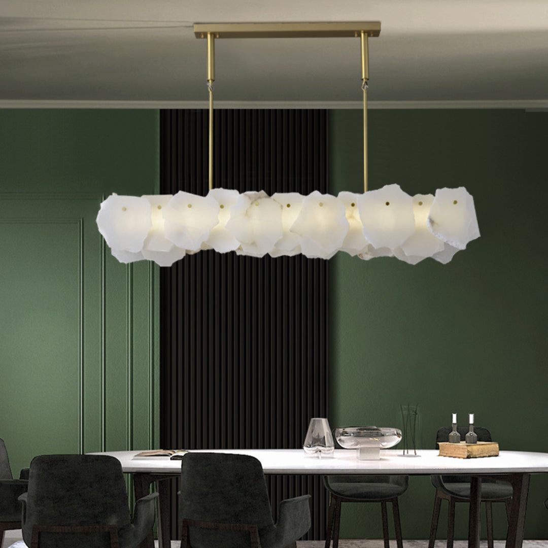 Clérachic alabaster linear chandelier over a white dining table in a deep green room with a black slatted panel