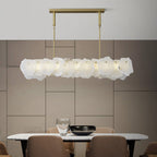 Clérachic alabaster linear chandelier seen close over a marble dining table, brass rods rising to the ceiling plate