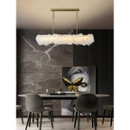 Clérachic alabaster linear chandelier above an oval dining table against brown marble and dark slatted panelling