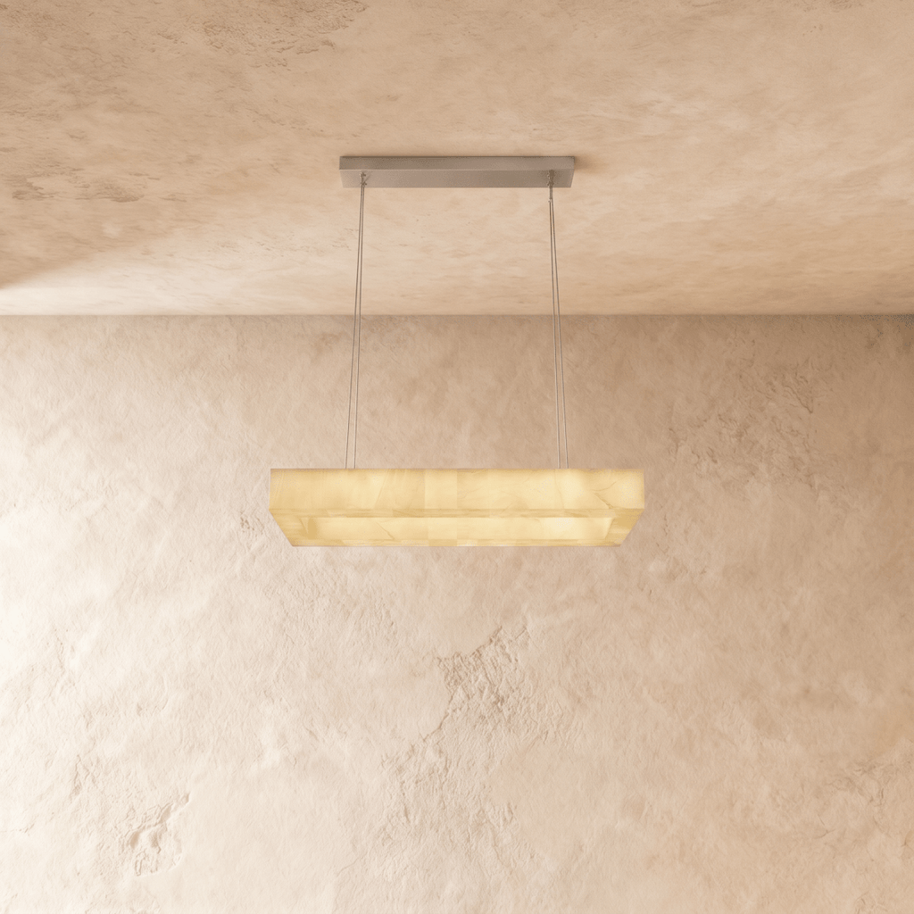 Clérachic rectangular alabaster chandelier on two steel cables with a slim metal canopy, glowing warm against limewash.