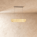 Clérachic rectangular alabaster chandelier on two steel cables with a slim metal canopy, glowing warm against limewash.