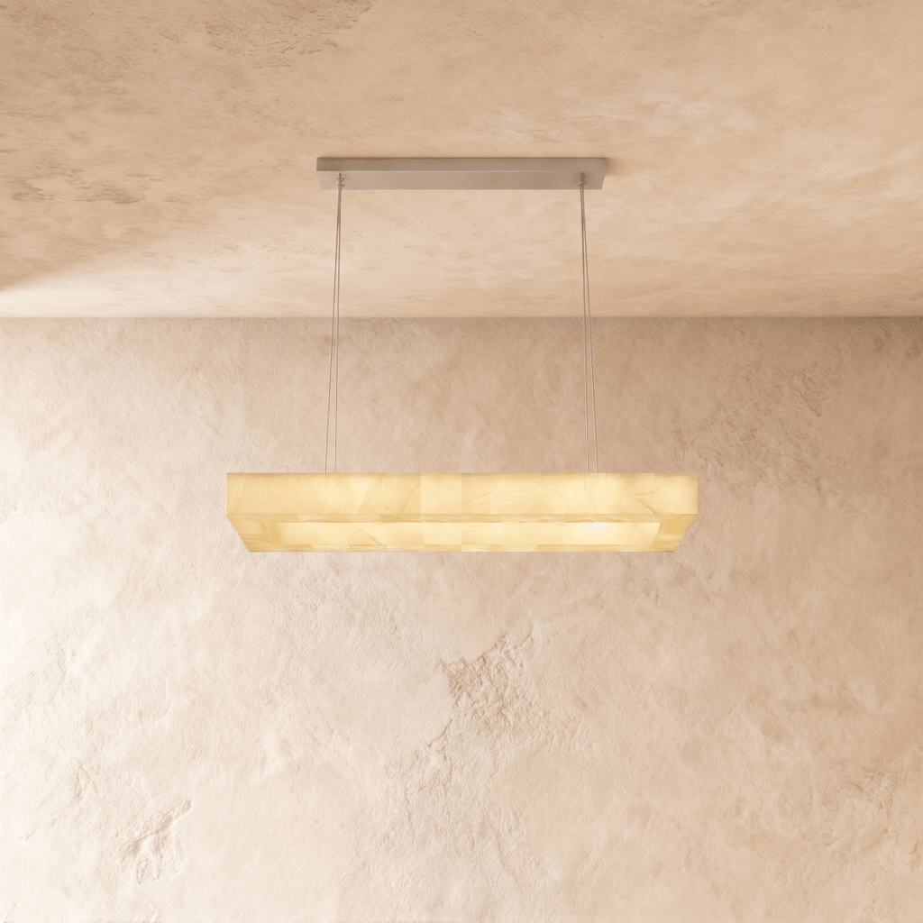 Clérachic rectangular alabaster chandelier in a longer size, warm light glowing through the veined stone shade.