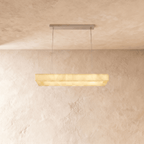 Clérachic rectangular alabaster chandelier in a longer size, warm light glowing through the veined stone shade.