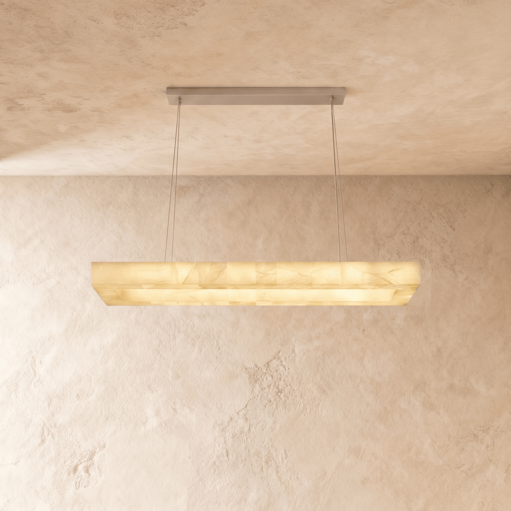 Clérachic longer rectangular alabaster chandelier hung from a brushed metal canopy on thin cables, lit warm.