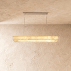 Clérachic longer rectangular alabaster chandelier hung from a brushed metal canopy on thin cables, lit warm.